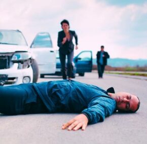 Pedestrian motionlessly lying on the ground after a car accident