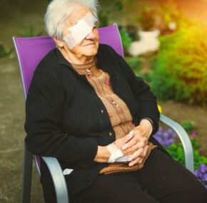 Senior female with injury sitting on a chair outside nursing home