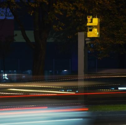 A photo of a speed camera and light trails of moving vehicles