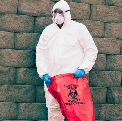 Man in protective suit holding a hazardous waste bag