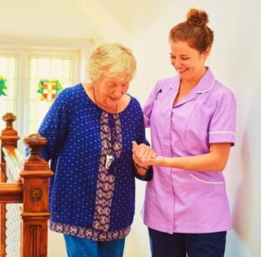 A nurse helps senior woman climb the stairs of the nursing home
