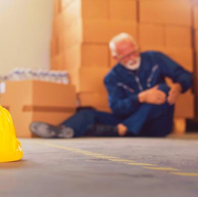 Senior warehouse worker sitting on the floor after hurting himself from not stretching before working