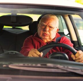 Old man looking angry driving a car