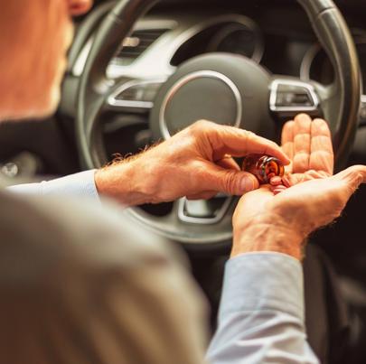 man pouring pills into hand while inside the car