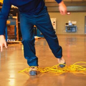 A worker tripping over an electrical cord in an industrial environment