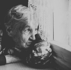Emotionally abused elderly woman sitting near the window in a nursing home