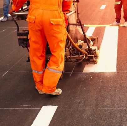 Road worker painting crosswalk on asphalt road