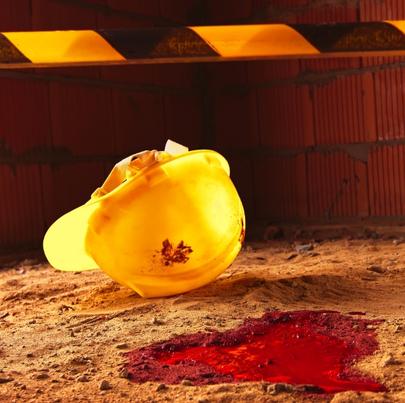 Image of a yellow hard hat with blood on the floor after a fatal accident