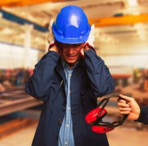 A worker wearing hard hat protecting his ear from hazardous noise