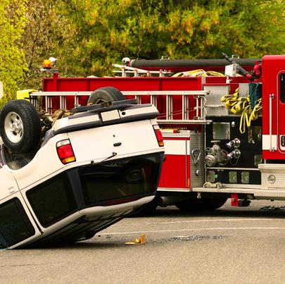 SUV crash with the vehicle upside down with firetruck on the background