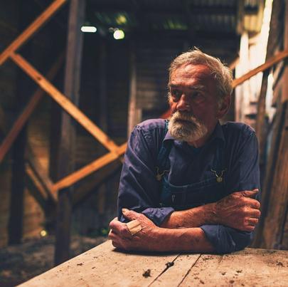 Lonely fold farmer sitting inside an old barn