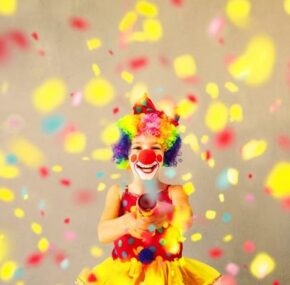 Funny kid clown with party poppers.