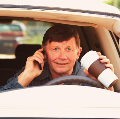 Man talking on the phone and drinking coffee while driving