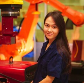 Female manufacturing worker operating a robot machine