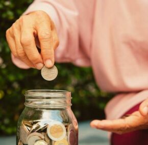 Elderly adding penny in a jar