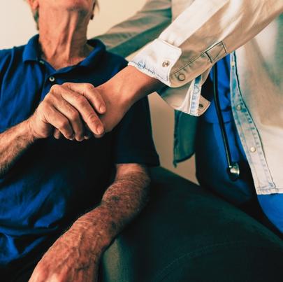 Elderly man holding the hands of his medical caregiver in a nursing home