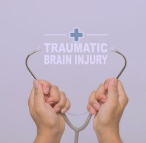 Hands holding a stethoscope and word 'traumatic brain injury' medical concept