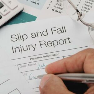 Close up of Slip and Fall injury Form with pen, calculator and writing hand