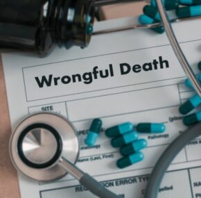 wrongful death printed on a paper with stethoscope and medicines)