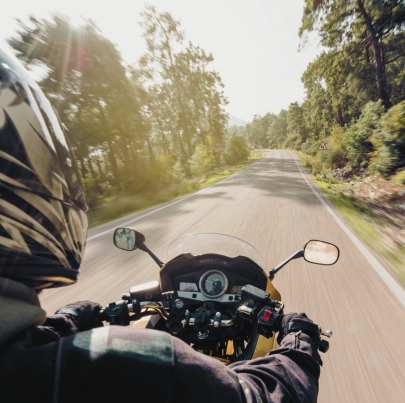 Motorcycle speeding down on an empty country road from over rider’s point of view. How motorcycle laws prevent catastrophic injuries