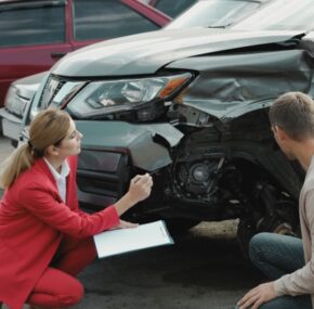 Man reporting and insurance agent filling claim form near broken car outdoors. Concept of What Are the Dangers of Driving a Car Without Insurance