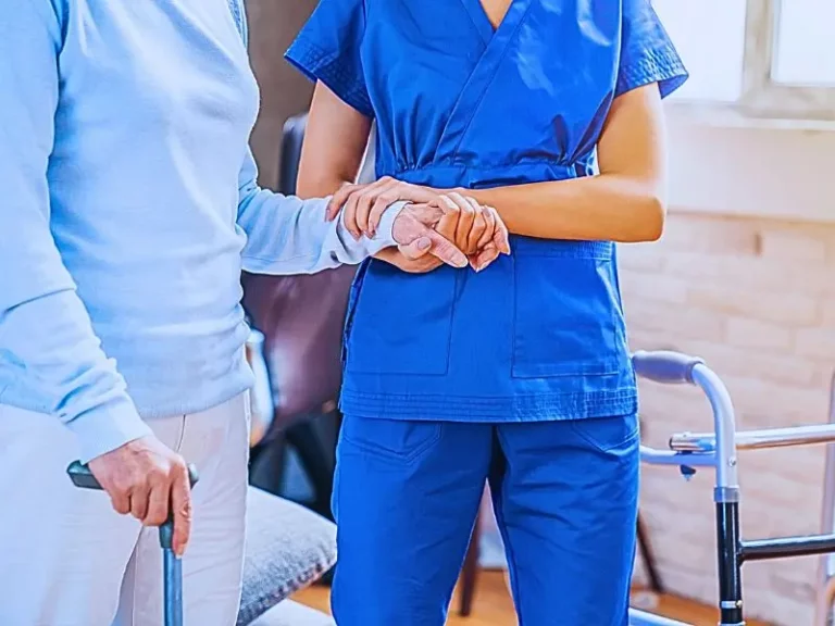 Cropped of female social worker helping senior woman to walk with walker at home. nursing home laws and regulations