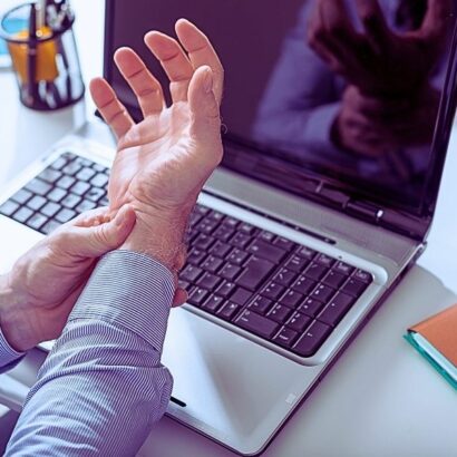 Businessman suffering from wrist pain in office. Workers' comp nerve damage settlement