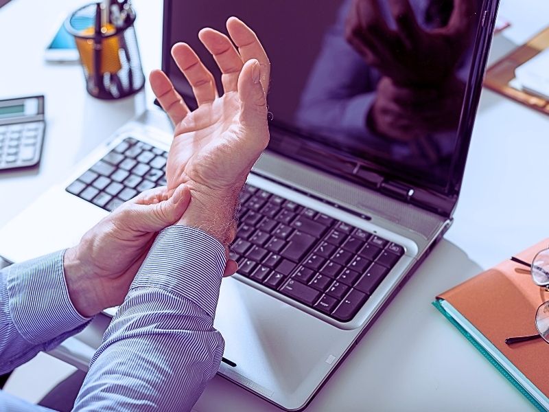 Businessman suffering from wrist pain in office. Workers' comp nerve damage settlement