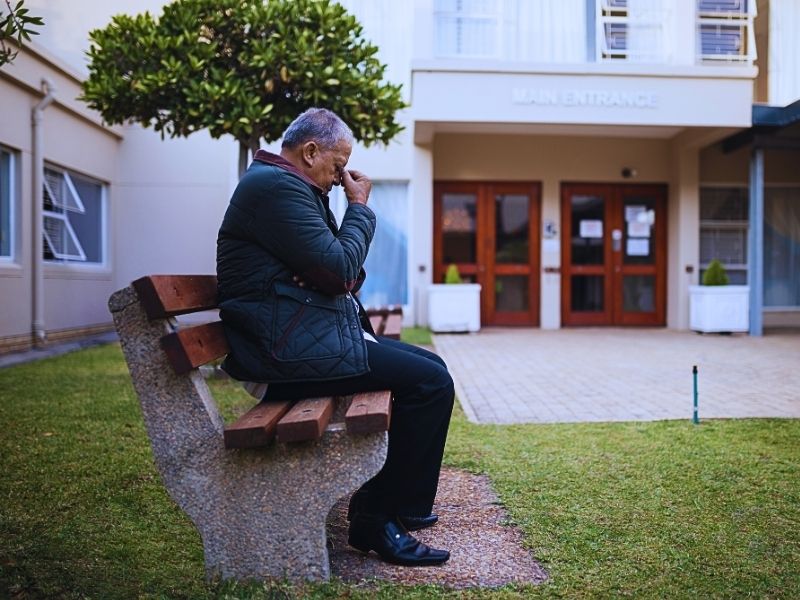 Depressed senior man sitting on bench. Nursing home neglect