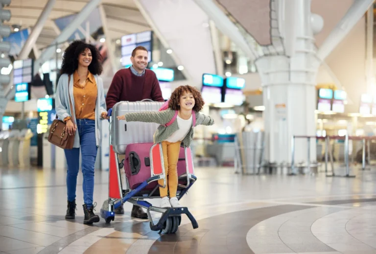 Family smiling as they push a cart through the airport during holiday travel
