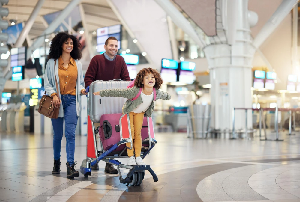 Family smiling as they push a cart through the airport during holiday travel